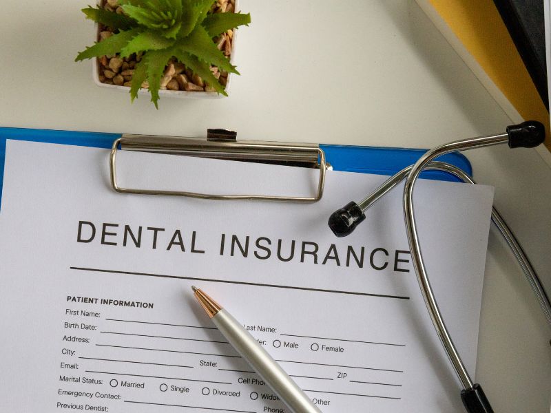 Dental insurance form with pen and stethoscope on desk.