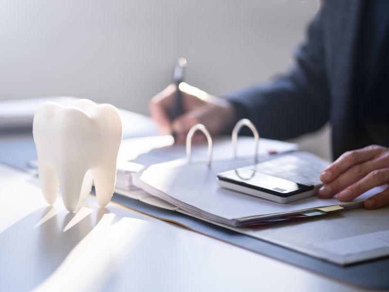 Alt text: Dental model with paperwork and calculator.